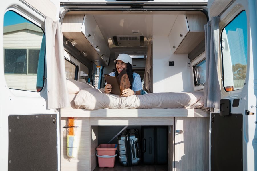 Vrouw ligt op bed in de Cruisin' Sandpiper met de achterdeuren open