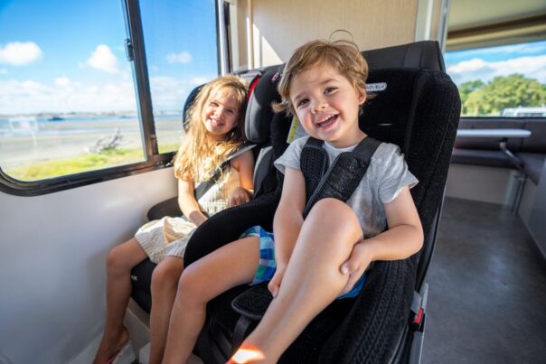 Twee kinderen zitten in kinderautostoelen in de camper