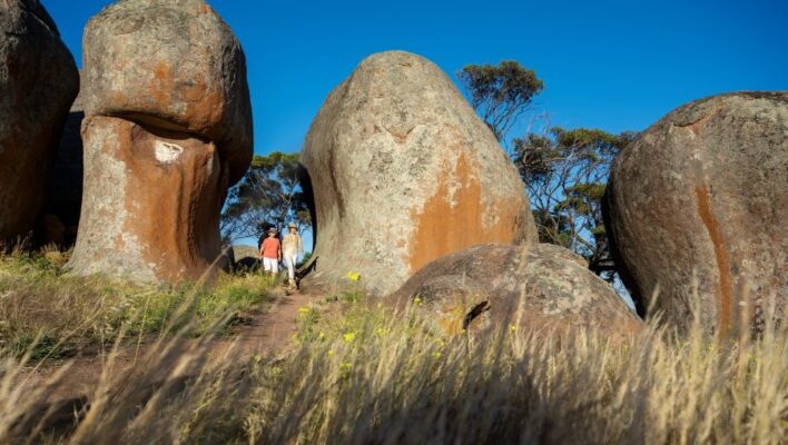 Man en vrouw lopen tussen de rotsen van Murphy's Haystacks in South Australia