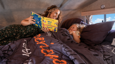 Moeder leest voor in bed in de alkoof van de camper aan jong kind