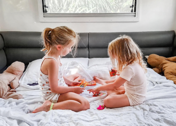 Twee kinderen spelen een spelletje op bed in de Maui Beach camper