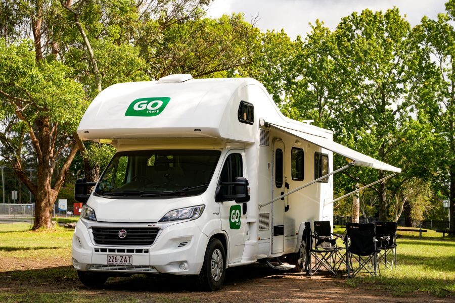 Go Cheap Derwent staat geparkeerd op een camping, stoelen buiten onder de luifel