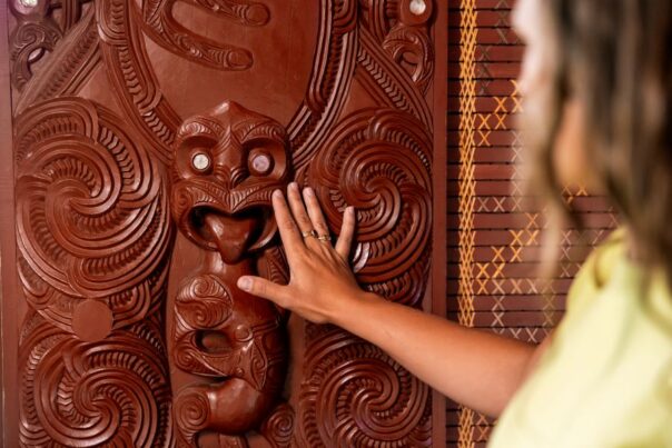 Vrouw raakt Maori houtsnijwerk aan in Rotorua
