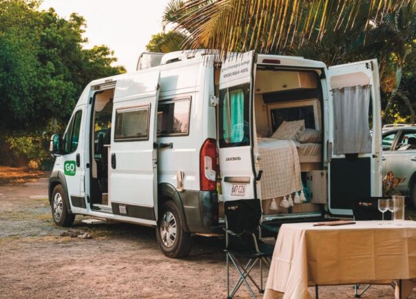 Go Cheap Tamar geparkeerd op een camping met de zij- en achterdeuren open en stoelen met tafel buiten