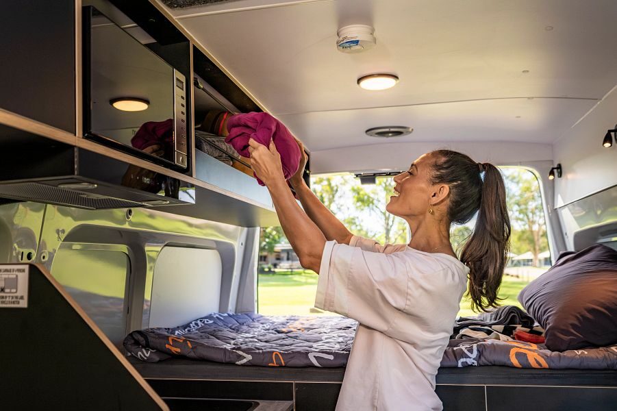 vrouw legt handdoek in bovenkast in de Britz Hitop camper in Australië