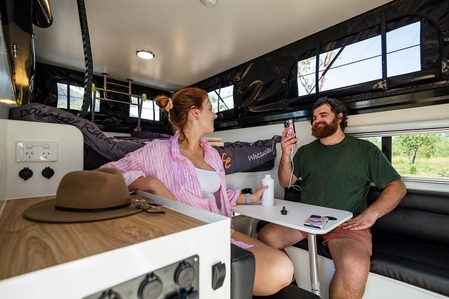 koppel zit binnen aan tafel in de zithoek naast het bed in de Britz Maverick 4WD