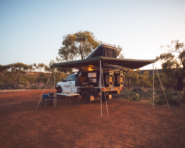 De RedSands 4WD camper is volledig opgesteld in een mooie omgeving met de royale luifel en gereed voor de nacht met de opengeklapte daktent