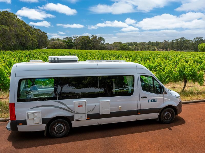 De Maui Ultima Plus camper van de zijkant geparkeerd naast een wijngaard
