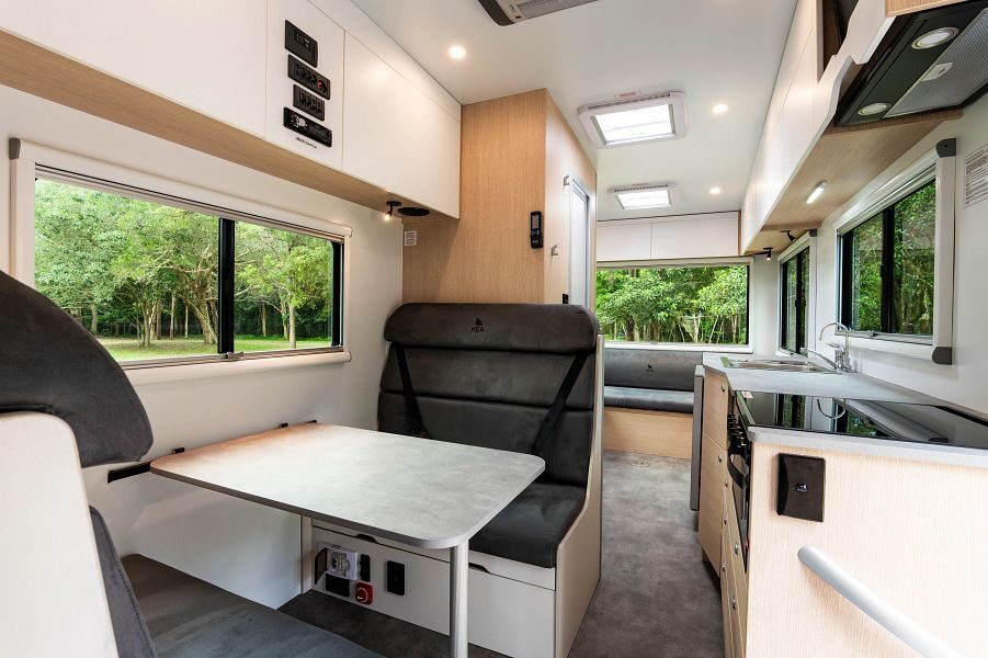 Het interieur van de Maui River camper gezien vanaf de bestuurdersruimte kijkend naar de achterkant van de camper met zitplaatsen in het midden, de keuken en achterin nog een zithoek