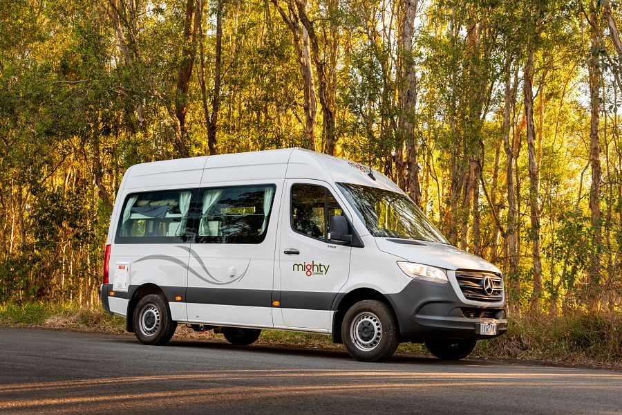 De Mighty Highball camper staat op de weg voor het bos vanaf de zijkant gezien