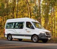 De Mighty Highball camper staat op de weg voor het bos vanaf de zijkant gezien
