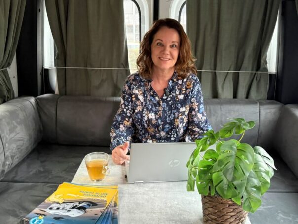Karin Kramer zit in de camper met kop thee en laptop