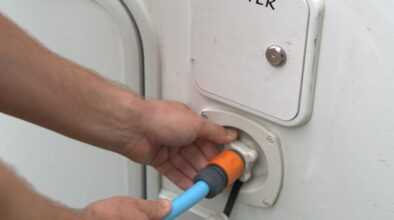 Man sluit waterslang aan op de camper