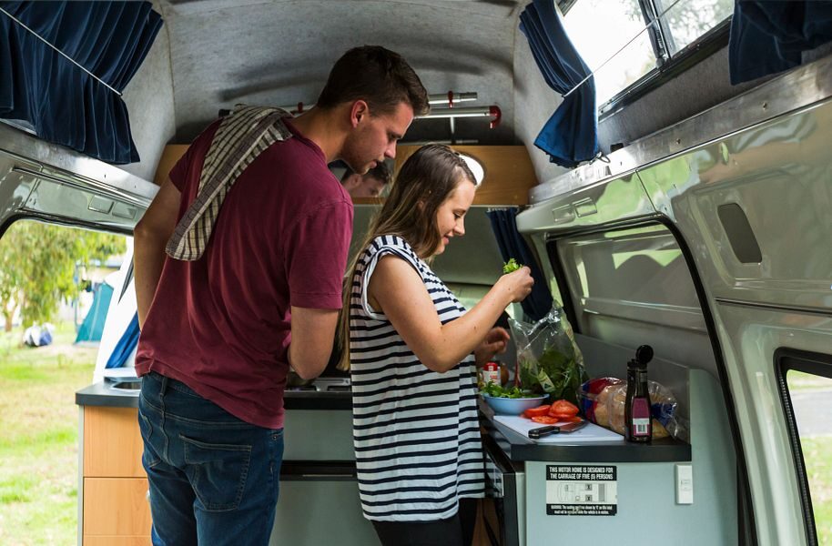 Een stel is aan het koken in de keuken van de Mighty Lite HiLITE camper in Australië
