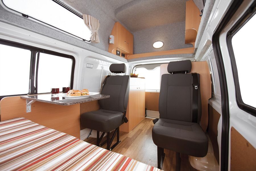 De twee zitplaatsen met gordels en tafeltje in het midden van de Mighty Lite DeLITE camper in Australië