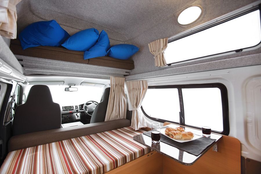Het interieur met een bank en tafel waar broodjes en drinken op staat van de Mighty Lite DeLITE in Australië