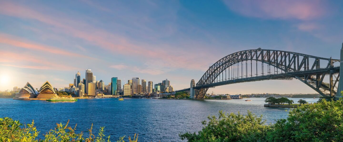 Skyline van Sydney met het Opera House en de Harbour Bridge bij zonsondergang