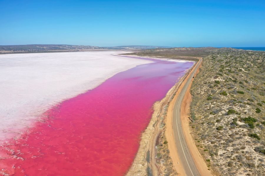 Dronebeeld van Hutt lagoon en het roze meer met een weg erlangs
