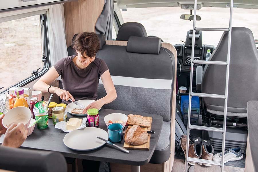 Een vrouw is een boterham aan het smeren aan tafel in de McRent Family Luxury
