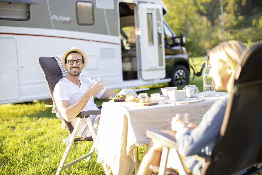 Een man zit tegenover zijn vrouw op een campingstoel aan de zijkant van de McRent Comfort Plus