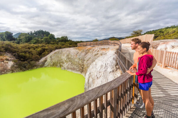 Een koppel staat bij Wai-O-Tapu te kijken naar de geothermische bronnen