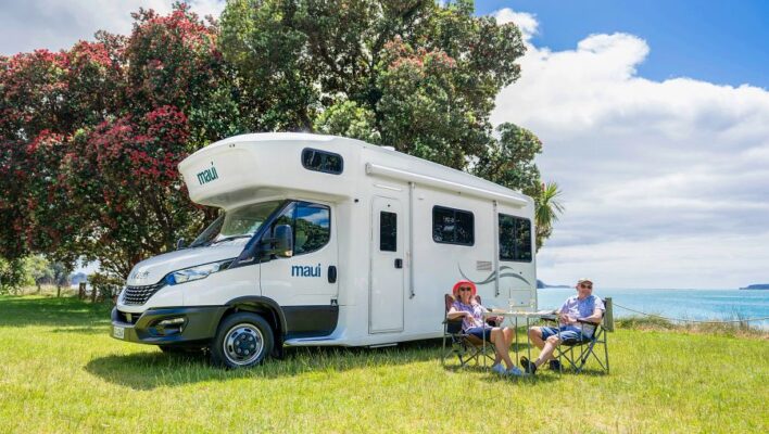 Een koppel zit voor de Maui Beach camper in de omgeving van Auckland