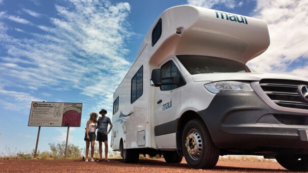 Stel staat naast Maui River om bord te lezen onderweg naar Broome