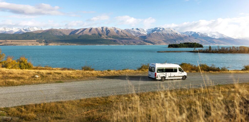 De Maui Ultima rijdt over een weg langs Lake Wanaka met uitzicht op de bergen