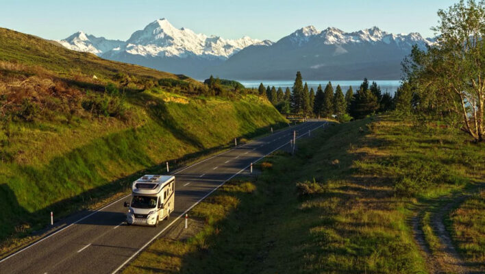 De Britz Wanderer rijdt over een weg met op de achtergrond Lake Pukaki en besneeuwde bergtoppen