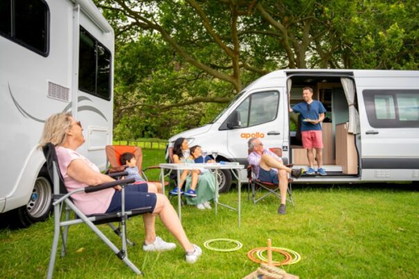 Gezinnen met kinderen staan met een Maui River en een Apollo Euro Plus camper op een locatie in een boomrijke groene omgeving