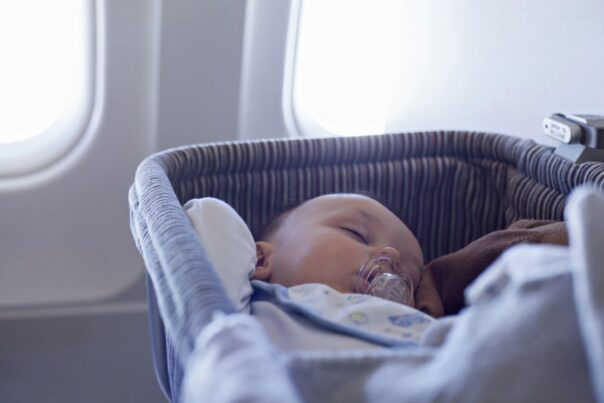Baby slaapt met speen in de mond in een bassinet in een vliegtuig