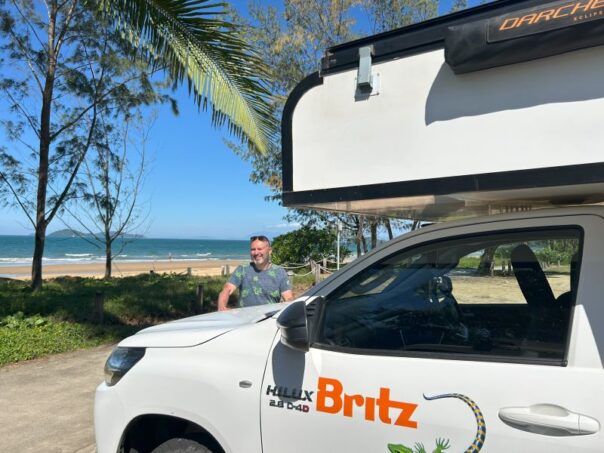 Peter Kramer staat bij de Britz Maverick aan het strand bij Mission Beach in Queensland