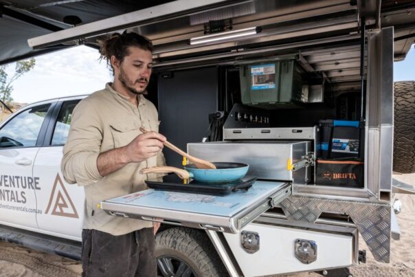 Man is aan het koken in de buitenkeuken van de Adventure Rentals Toyota Hilux 4WD