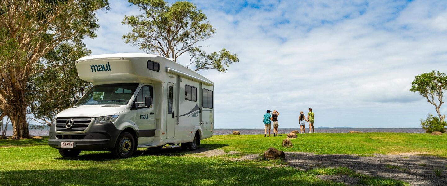 Maui River staat geparkeerd op gras in Australië Noosa en twee stellen kijken in de verte