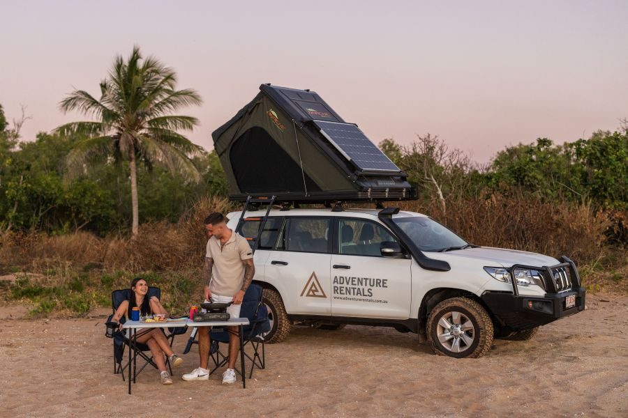 Stel zit aan tafel voor de Adventure Rentals Toyota Prado 4WD camper met het dak omhoog