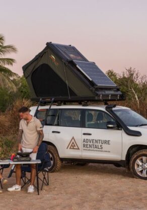Stel zit aan tafel voor de Adventure Rentals Toyota Prado 4WD camper met het dak omhoog