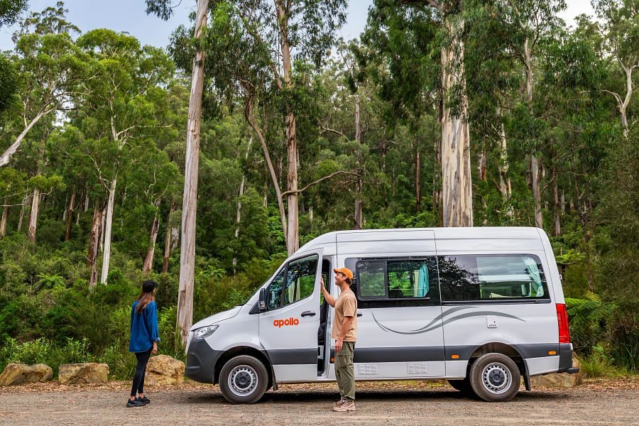 Apollo Endeavour staat geparkeerd in een bos in Australië, vrouw staat bij de open deur